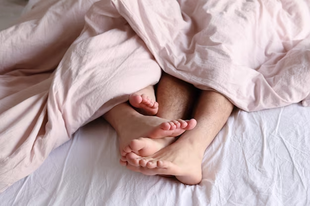 Two pairs of feet under the bed covers