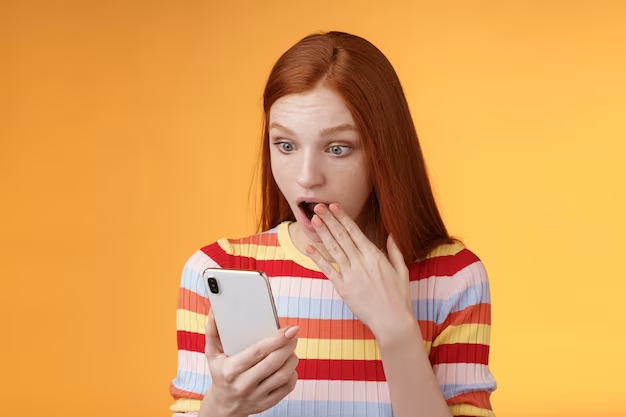 Woman with open mouth covering it with her hand while holding a phone
