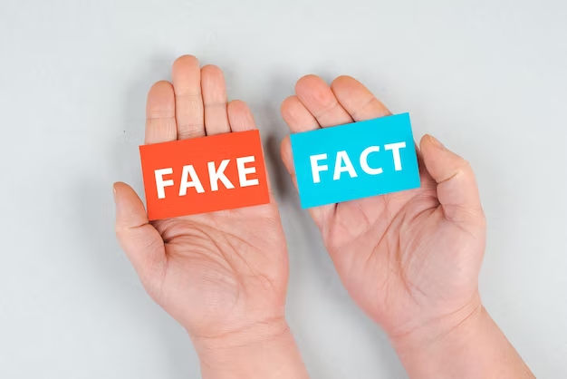 Hand holding two colored papers with words 'fake' and 'fact'