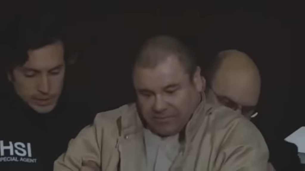 el chapo in a beige jacket surrounded by two men in black jackets on both sides