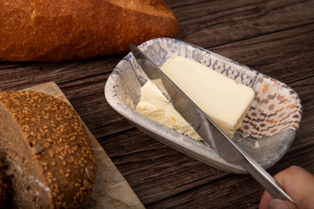 Close-up view of knife cutting butter and breads around